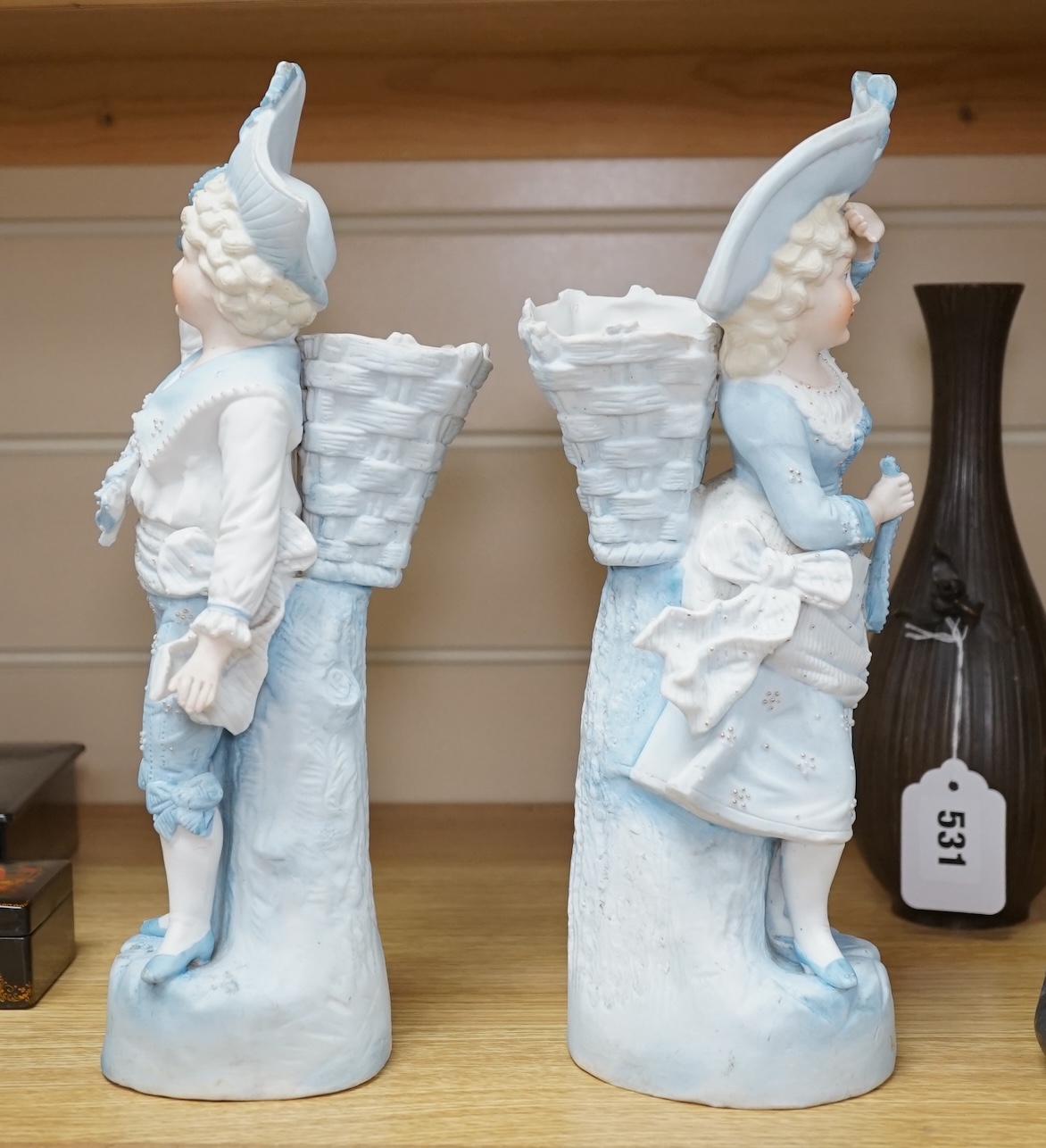 A pair of late 19th century German figurative bisque spill vases, 30cm high. Condition - good